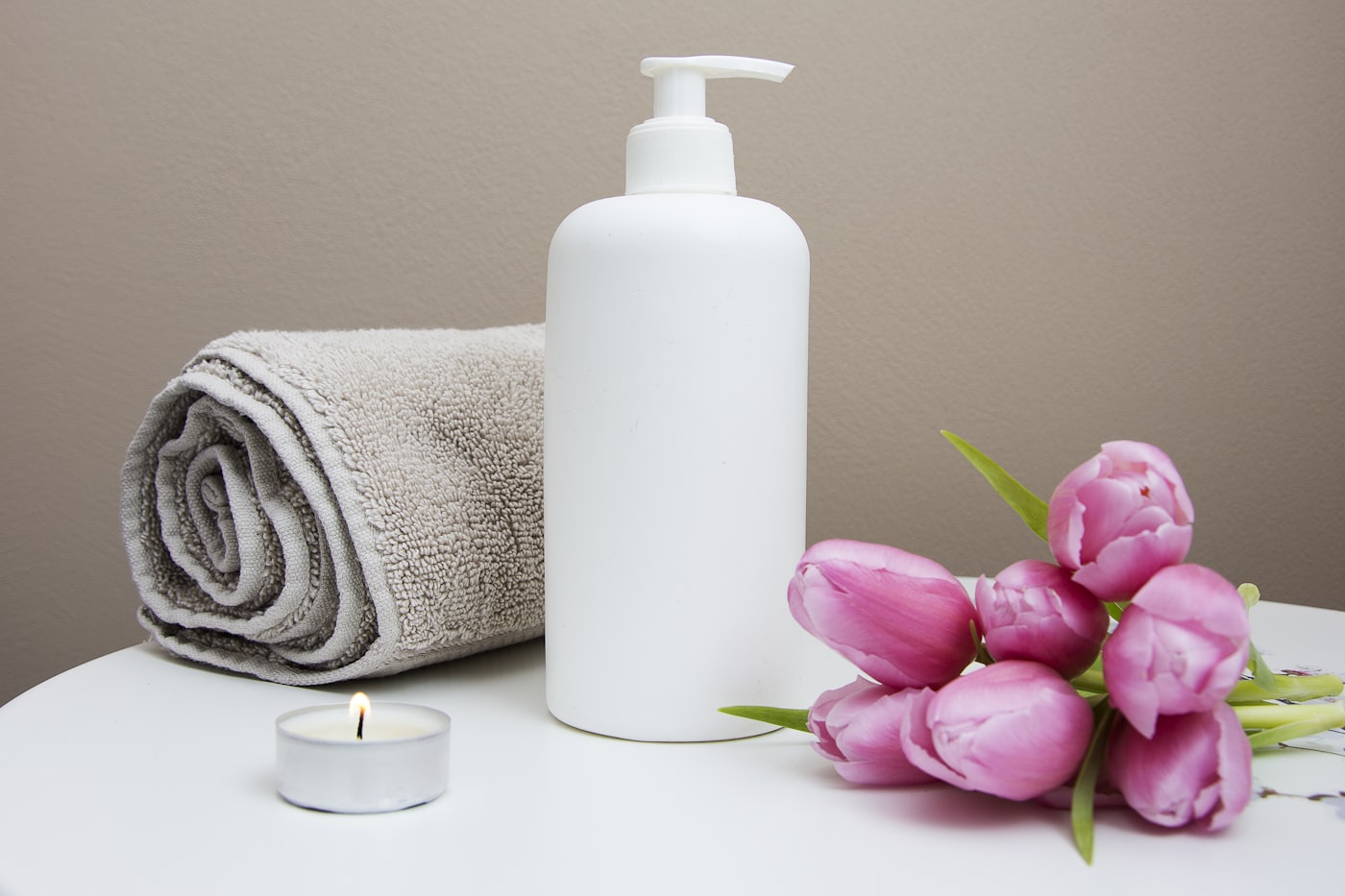 Ambiente de spa con toallas, velas y tulipanes rosas